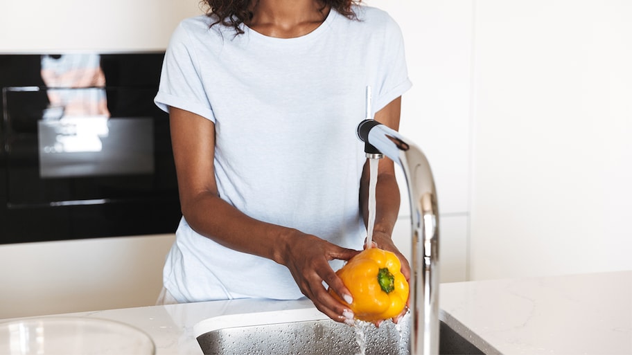 woman washing vegetables in sink